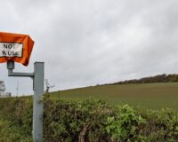 a sign on a pole next to a field of plants